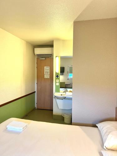 a room with a bed and a bathroom with a sink at Hotel Ibis Budget Cosne Sur Loire in Cosne Cours sur Loire