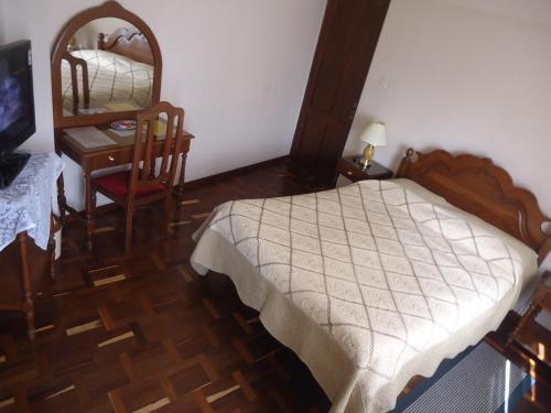 a bedroom with a bed and a desk and a mirror at Hostal España in Sucre