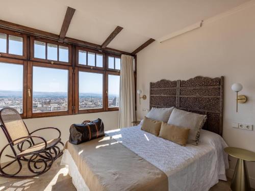 Schlafzimmer mit einem Bett, einem Stuhl und Fenstern in der Unterkunft Carmen de Azahar in Granada