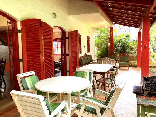 two tables and chairs on a patio with red shutters at Casa com muito lazer a 100m da Praia de Guaeca SP in Barequeçaba