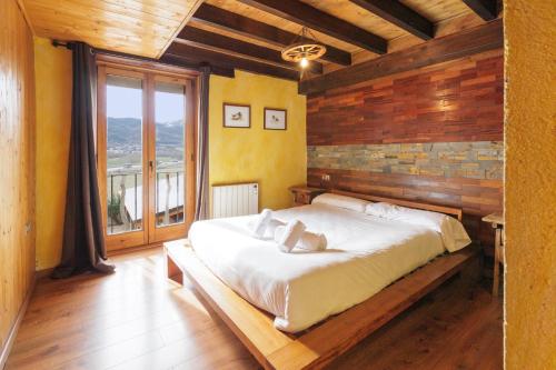 sypialnia z dużym łóżkiem i drewnianą ścianą w obiekcie Masia d'en cot w mieście Puigcerdà