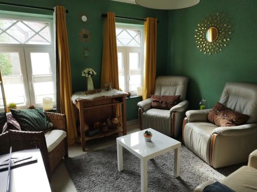 una sala de estar con paredes y sillas verdes y una mesa. en Maison d hôtes Les Notes Endormies " Suite La Mystérieuse" en Berzée