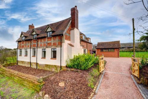 an old brick house with a fence in front of it at Fairview Cottage - Luxury Cottage with Hot Tub & Pizza Oven in Alvechurch