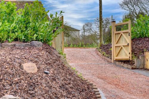 a garden with a wooden gate and a path at Fairview Cottage - Luxury Cottage with Hot Tub & Pizza Oven in Alvechurch