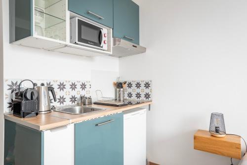 eine Küche mit Spüle und Mikrowelle in der Unterkunft Le 4K - Vue dégagée, Clim, Gare 10min à pied in Straßburg
