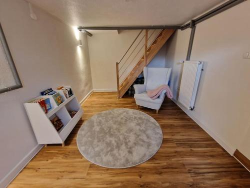 a living room with a staircase and a chair and a rug at Ferienhaus To Huus in Langen