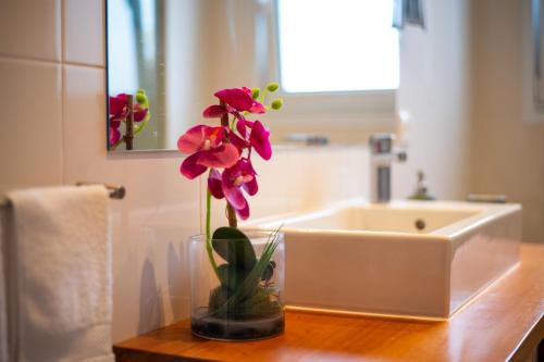 un vase avec des fleurs sur un comptoir dans la salle de bains dans l'établissement Alojamento Encantador no Centro de Ponta Delgada, à Ponta Delgada