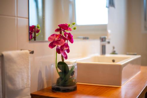 a vase with flowers on a counter in a bathroom at Alojamento Encantador no Centro de Ponta Delgada in Ponta Delgada