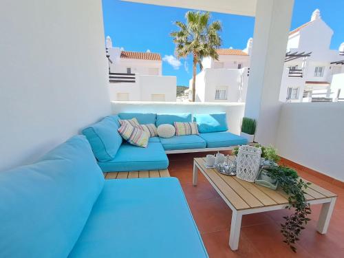 a living room with a blue couch and a table at Noctua Valle Romano Golf Estepona 003 in Estepona