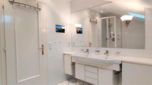 een witte badkamer met een wastafel en een spiegel bij Fewo Wetterstein in Garmisch-Partenkirchen