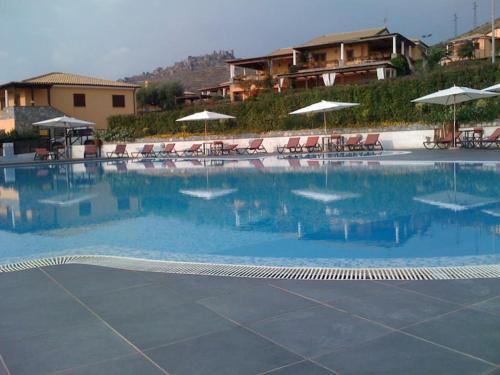 a large swimming pool with chairs and umbrellas at Luxury villa al mare in Calabria Diamante in Cirella