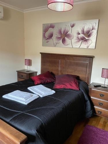 a bedroom with a black bed with two towels on it at Cantinho da Estrela in Seia