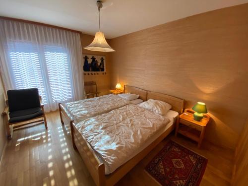 ein Schlafzimmer mit einem Bett, einem Stuhl und einem Fenster in der Unterkunft Apartment Corfou in Crans-Montana