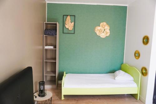 ein kleines Schlafzimmer mit einem Bett und einer grünen Wand in der Unterkunft Family' appart Narbonne Centre-ville Clim Wi-fi 2 chambres in Narbonne