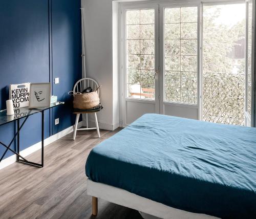une chambre avec des murs bleus et un lit et une fenêtre dans l'établissement Appartement avec balcon 10kms des plages, à Arzal