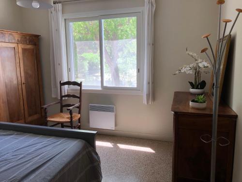 a bedroom with a bed and a window and a chair at Petite Maison en Provence in Arles