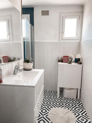 La salle de bains est pourvue d'un lavabo blanc et d'un sol noir et blanc. dans l'établissement Appartement avec balcon 10kms des plages, à Arzal