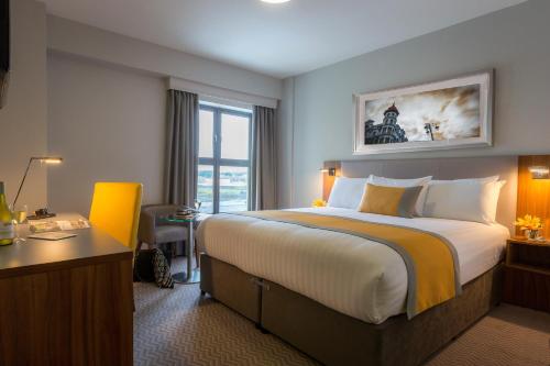 a hotel room with a large bed and a desk at Maldron Hotel Derry in Derry Londonderry
