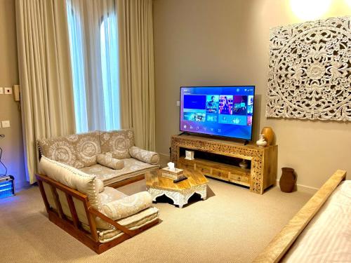een woonkamer met een televisie en een bank en stoelen bij شاليه مثوى الصباريات in Riyad