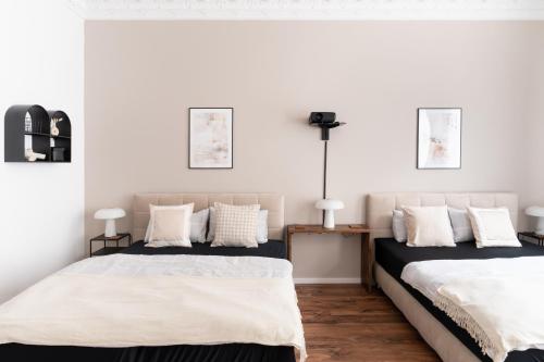 2 łóżka w sypialni z białymi ścianami i drewnianą podłogą w obiekcie Leipzig Residenz City-Center Apartments w Lipsku