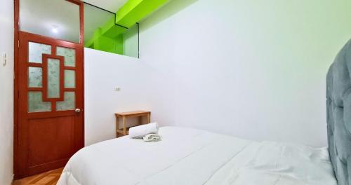 ein Schlafzimmer mit einem weißen Bett und einer Holztür in der Unterkunft QORY WASY in Cusco