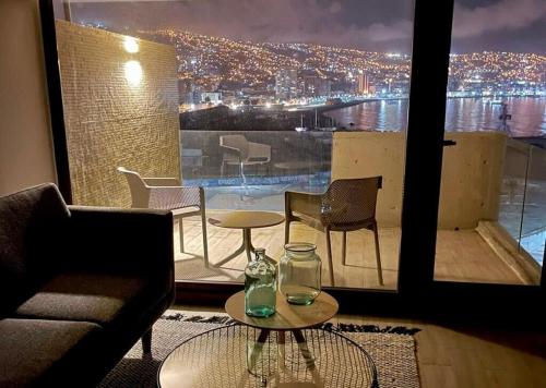 uma sala de estar com um sofá, uma mesa e uma grande janela em HOM I TOP1 NUEVO STUDIO en mejor zona Valparaíso Parking em Valparaíso