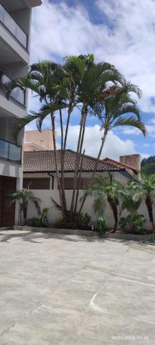 dos palmeras delante de un edificio en Residencial Canto das Flores, en Florianópolis