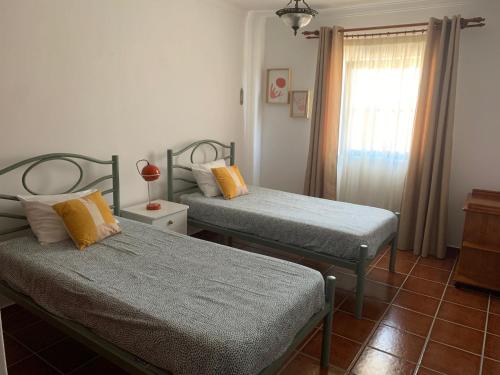 a bedroom with two twin beds and a window at Sesimbra Concept in Sesimbra