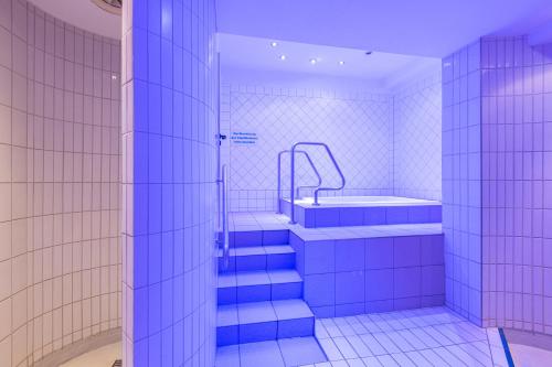 y baño con bañera y escaleras de azulejos azules. en IFA Schöneck Hotel & Ferienpark, en Schöneck