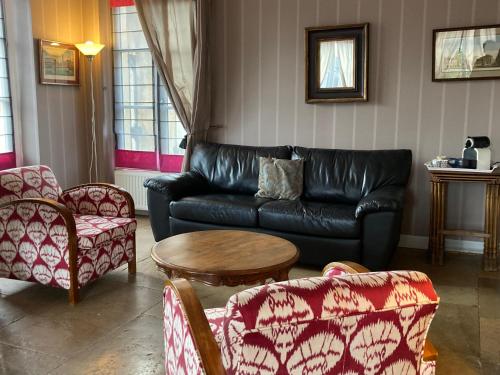 a living room with a black leather couch and chairs at B&B Vassy Etaule in Avallon
