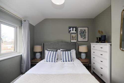 a bedroom with a bed with two pillows and a window at The Dagenham Park Place - Dazzling 3BDR House with Garden in Dagenham