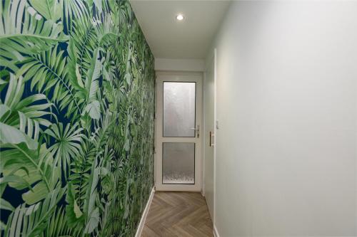 a hallway with a mural of plants on the wall at Inviting House near Skewen Park in Skewen