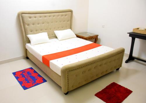 a bedroom with a bed with an orange and white comforter at Ranathisara Grand Hotel in Kurunegala