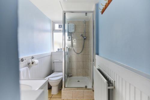 La salle de bains est pourvue d'une douche, de toilettes et d'un lavabo. dans l'établissement The Dagenham Park Place - Dazzling 3BDR House with Garden, à Dagenham