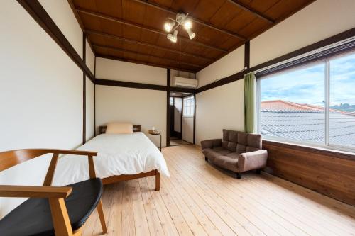 1 dormitorio con 1 cama, 1 silla y 1 ventana en 東のおうち en Hita