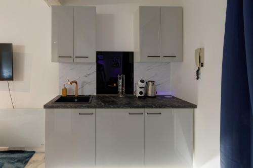 une cuisine avec des armoires blanches et un évier dans l'établissement Suite Romantique - Centre historique, Jacuzzi, wifi, 10min gare, à Montpellier