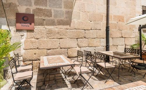 a group of tables and chairs next to a brick wall at Hotel Ilunion Mérida Palace in Merida