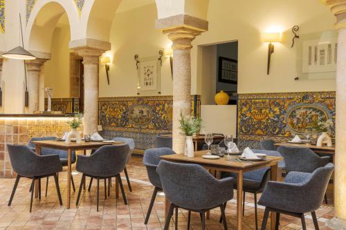 a restaurant with tables and chairs and a wall at Hotel Ilunion Mérida Palace in Merida