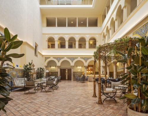 a lobby with chairs and tables in a building at Hotel Ilunion Mérida Palace in Merida