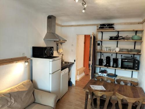 a kitchen and dining room with a table and a refrigerator at A découvrir joli petit Appart au coeur du village in Vallouise