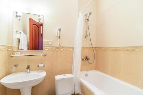 a bathroom with a sink and a toilet and a bath tub at Ukraine Hotel in Kyiv