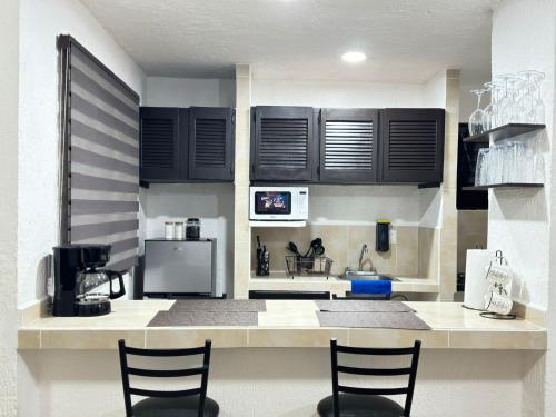 カンクンにあるCasa Marinaのキッチン(黒いキャビネット、椅子付きカウンター付)