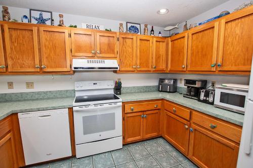 a kitchen with wooden cabinets and white appliances at Oceanside, Hot Tub, Rec Room, OD1, The Sandy Dune in Duck
