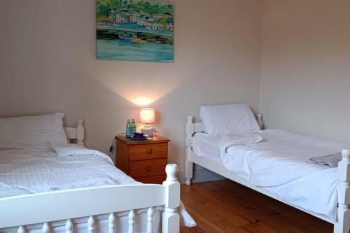 een slaapkamer met 2 witte bedden en een nachtkastje bij Valentia Island Escape in Valentia Island
