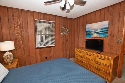 a bedroom with a bed and a tv on a wooden wall at Oceanside, Hot Tub, Rec Room, OD1, The Sandy Dune in Duck