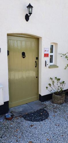 a large green garage door next to a building at Vale View Cottages -The Coach House in Prestatyn