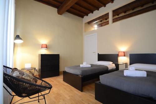 een slaapkamer met 2 bedden en een stoel. bij Palazzuolo 112 - Keys Of Italy in Florence