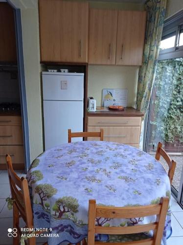 une cuisine avec une table et un réfrigérateur blanc dans l'établissement Rez de jardin Pinède Proximité Quartier Naturiste, au Cap d'Agde