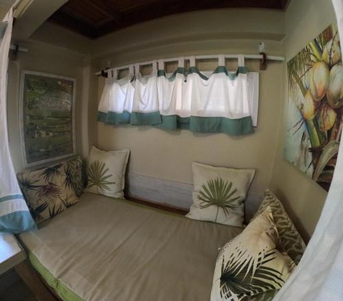 um pequeno quarto com duas almofadas e uma janela em Coconut Castle at La Lodge at Long Bay em Big Corn Island