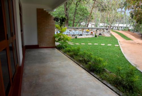 a walkway leading to a yard with a park at Ranathisara Grand Hotel in Kurunegala